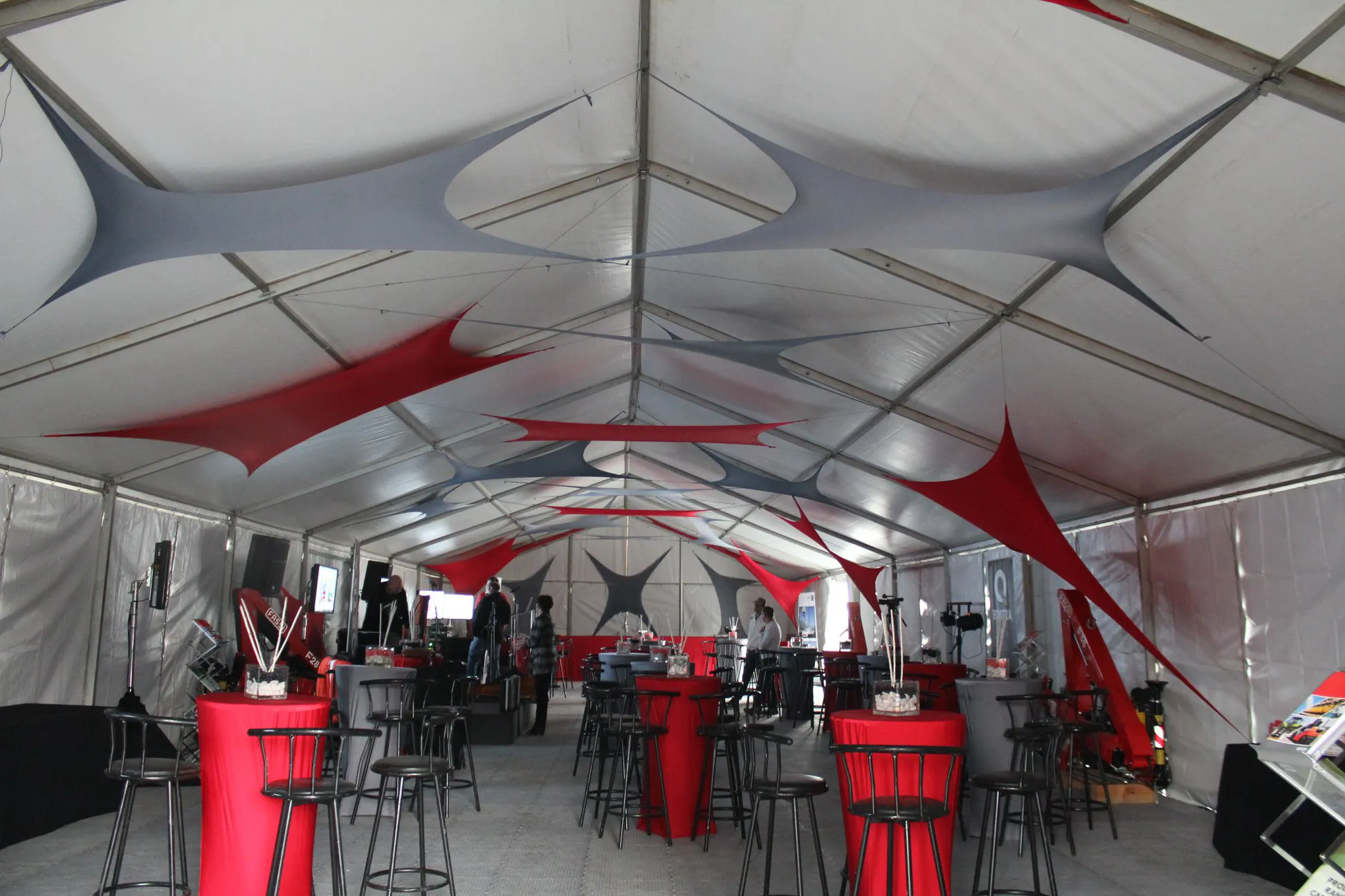 A corporate frame tent with red stretch panels and bar tables