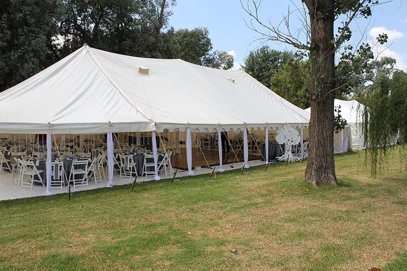 A peg and pole marquee under willow trees