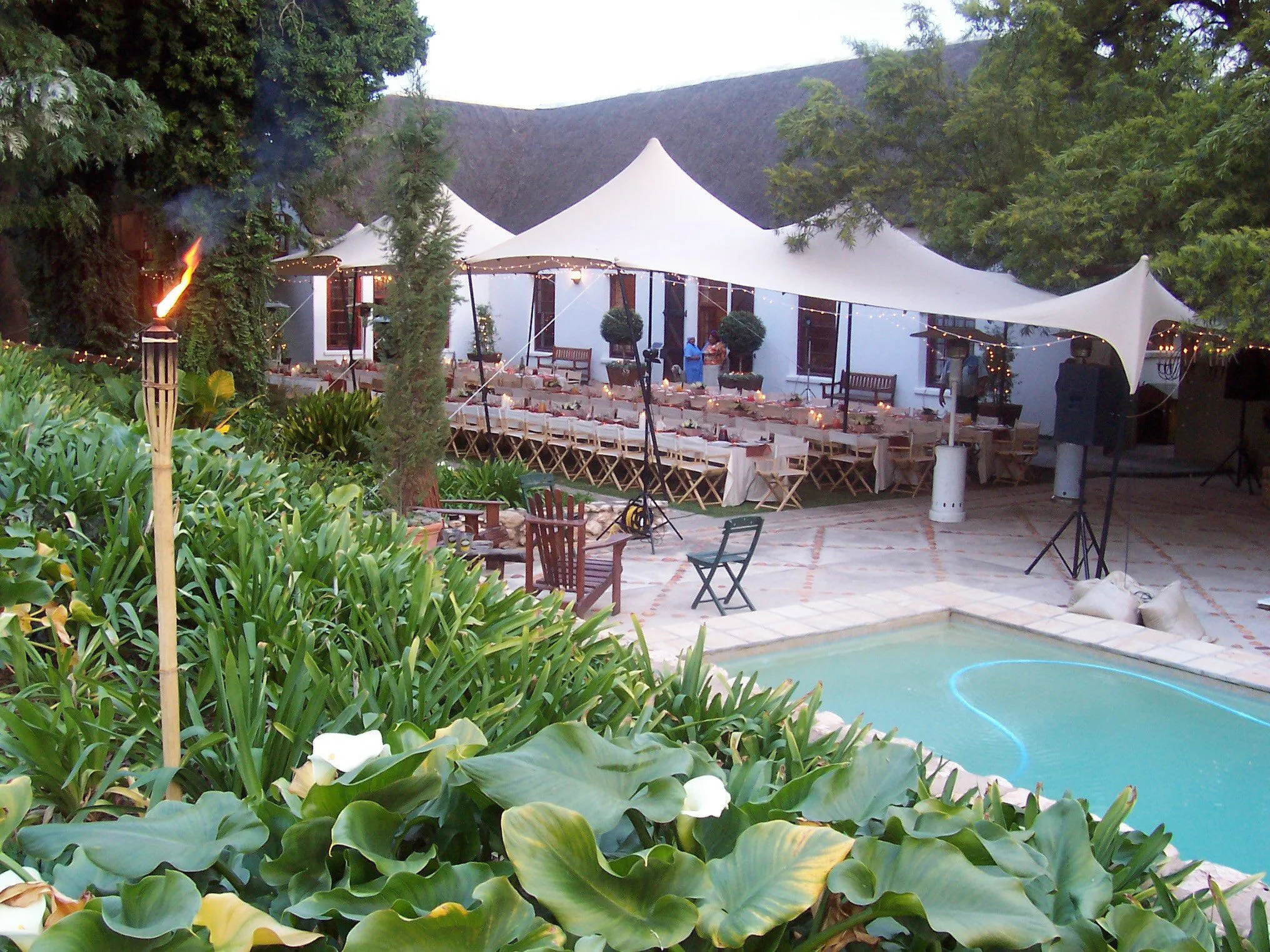 A stretch tent beside a pool with tables set underneath
