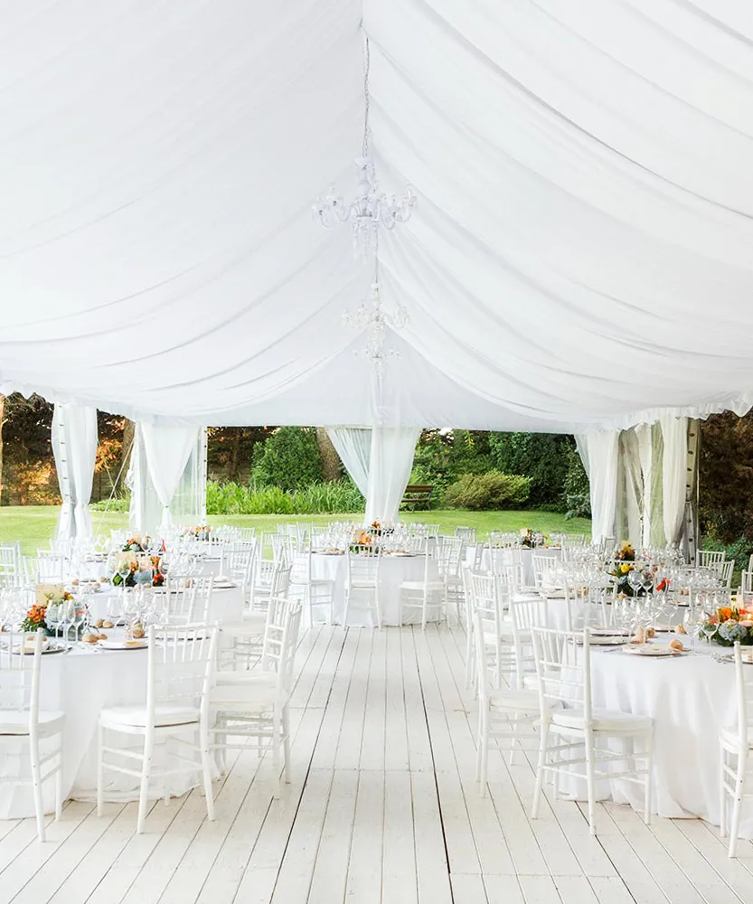 A white wedding setting inside a draped tent